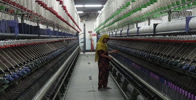  A worker monitors bobbins in a top-tier, mechanized factory. Photo credit Bishawjit Das.  
